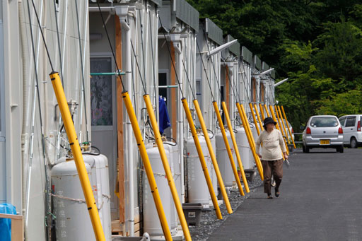 A woman walks by the rows of temporary housings for the March 11 earthquake and tsunami survivors at Hibiki Industrial Park in Higashimatsushima, Miyagi Prefecture, northeastern Japan, Tuesday, June 14, 2011. (AP Photo/Koji Sasahara)