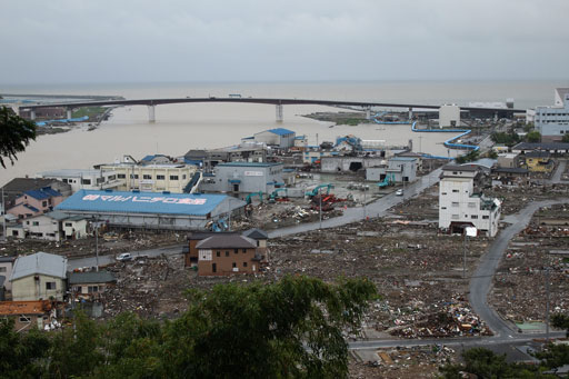 June 27 photo of right side of Kitakami River in Ishinomaki City. Debris was cleared from roads but still remained in the town. Building with blue roof on left is a fish processing factory. (Photo by Kyoritsu Risk Management)