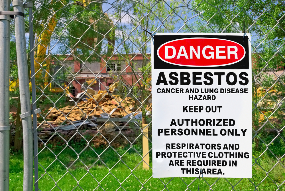 Asbestos removal sign on fence in front of building