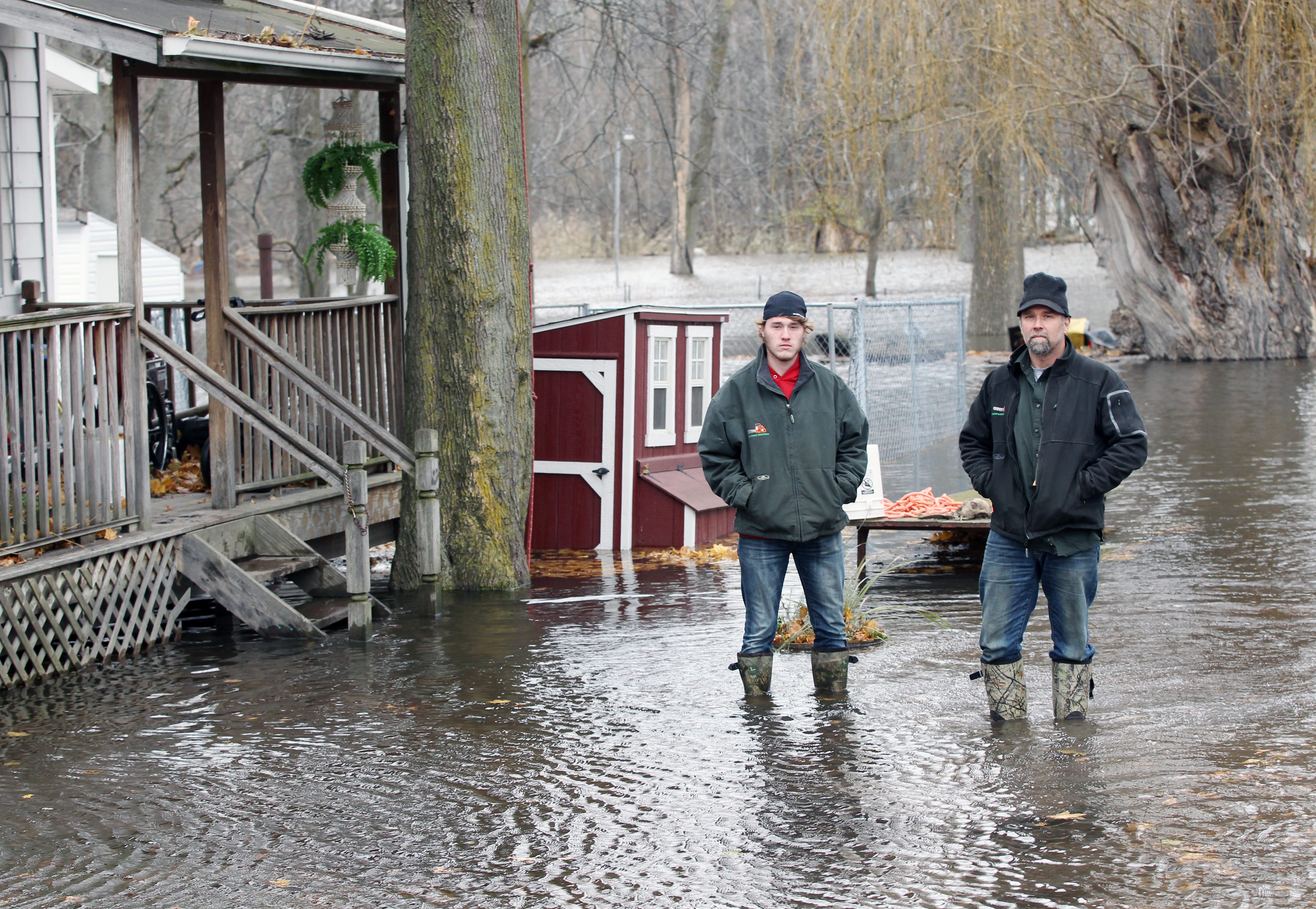 Jake Sojka, left, and his father Gregory Sojka, stand alongside their flooded home on Main Street in Bowmansville, N.Y., after Ellicott Creek crested its banks Tuesday, Nov. 25, 2014. 