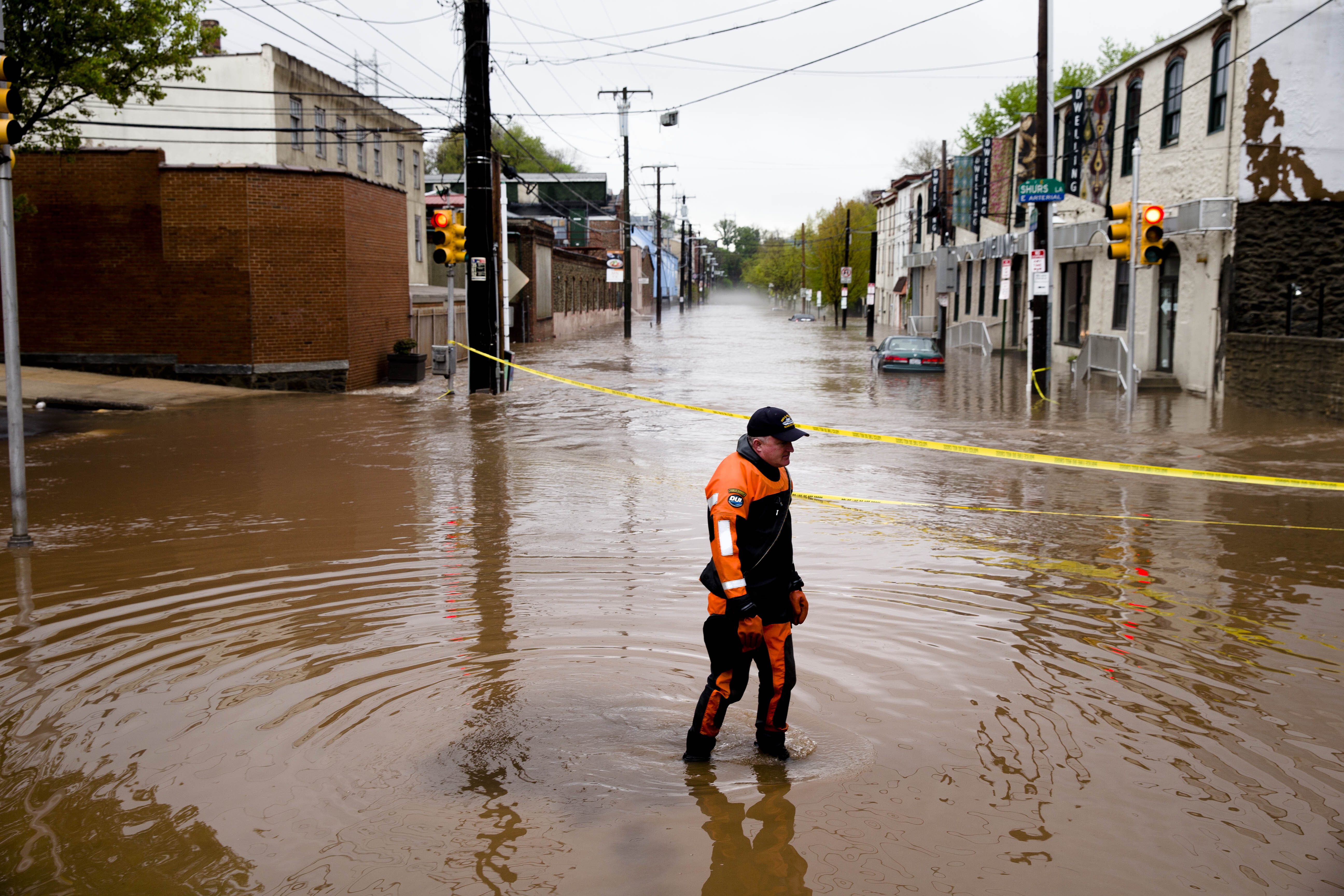 In this May 1, 2014 file photo, Marine unit police officer Robert Jonah walks through flood waters from the Schuylkill River on Main Street, Thursday, May 1, 2014, in the Manayunk neighborhood of Philadelphia. 