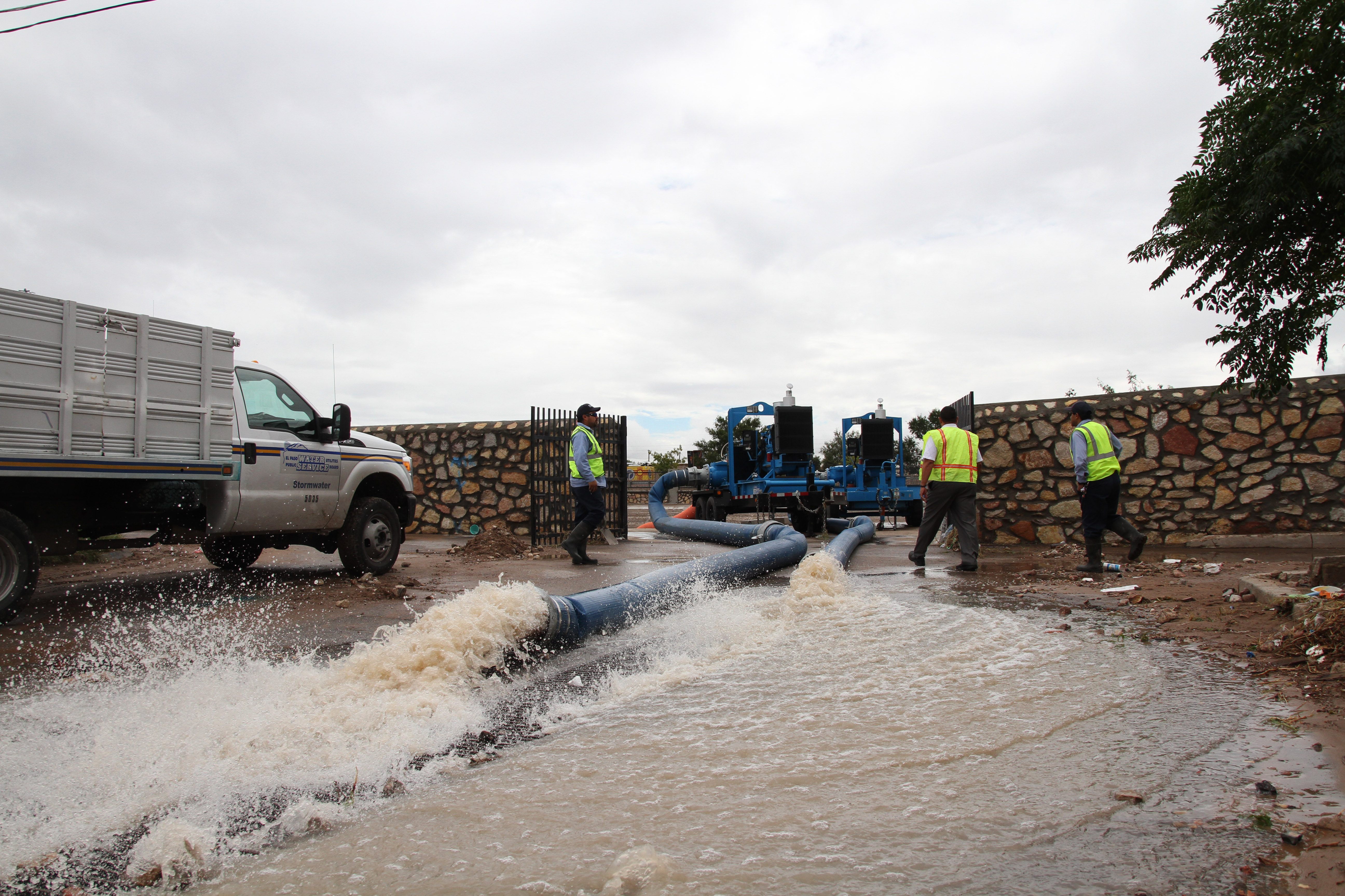 El Paso water utilities workers walk toward a pump that is emptying a storm water drainage pond in El Paso, Texas, Thursday, Sept. 18, 2014. 