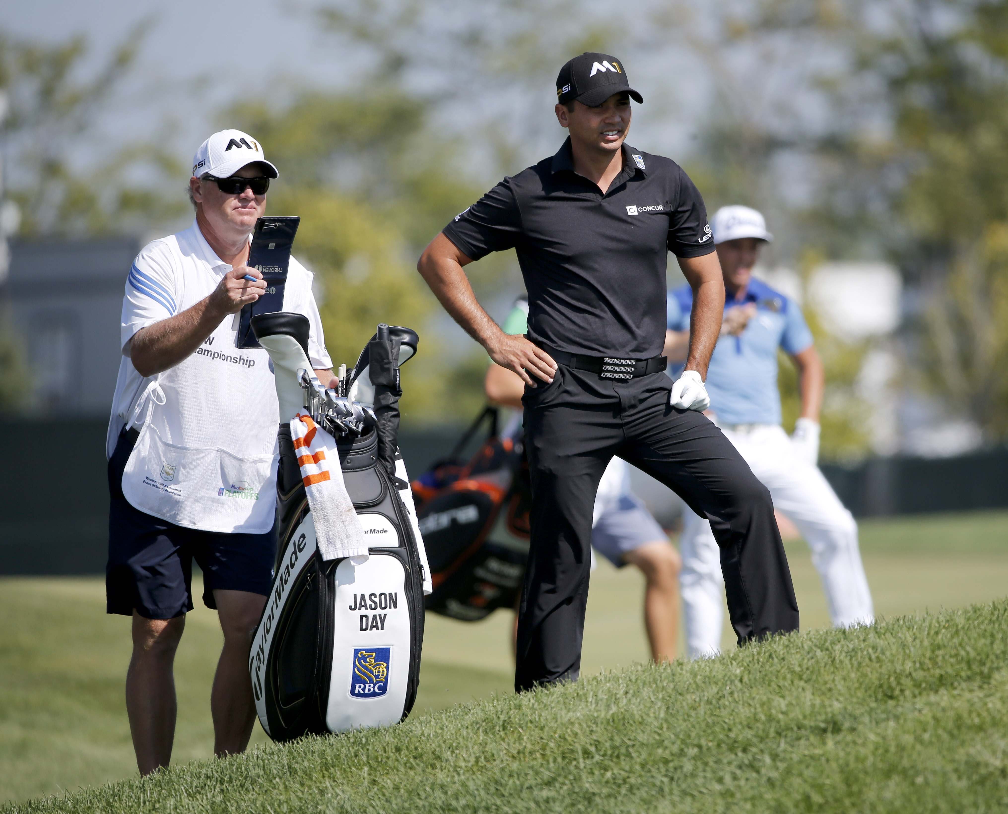 Jason Day, right, of Australia, looks over his shot from the rough with caddie Colin Swatten
