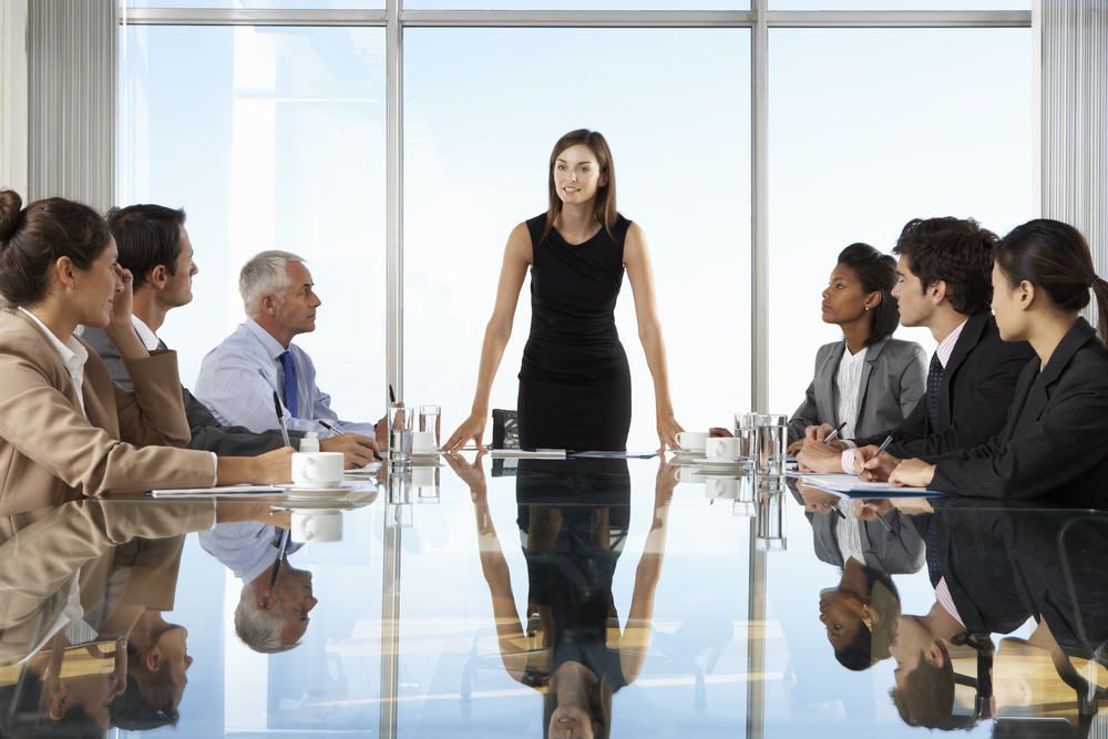 Woman-presenting-at-board-meeting-diverse-group-shutterstock_280366622-MonkeyBusinessImages