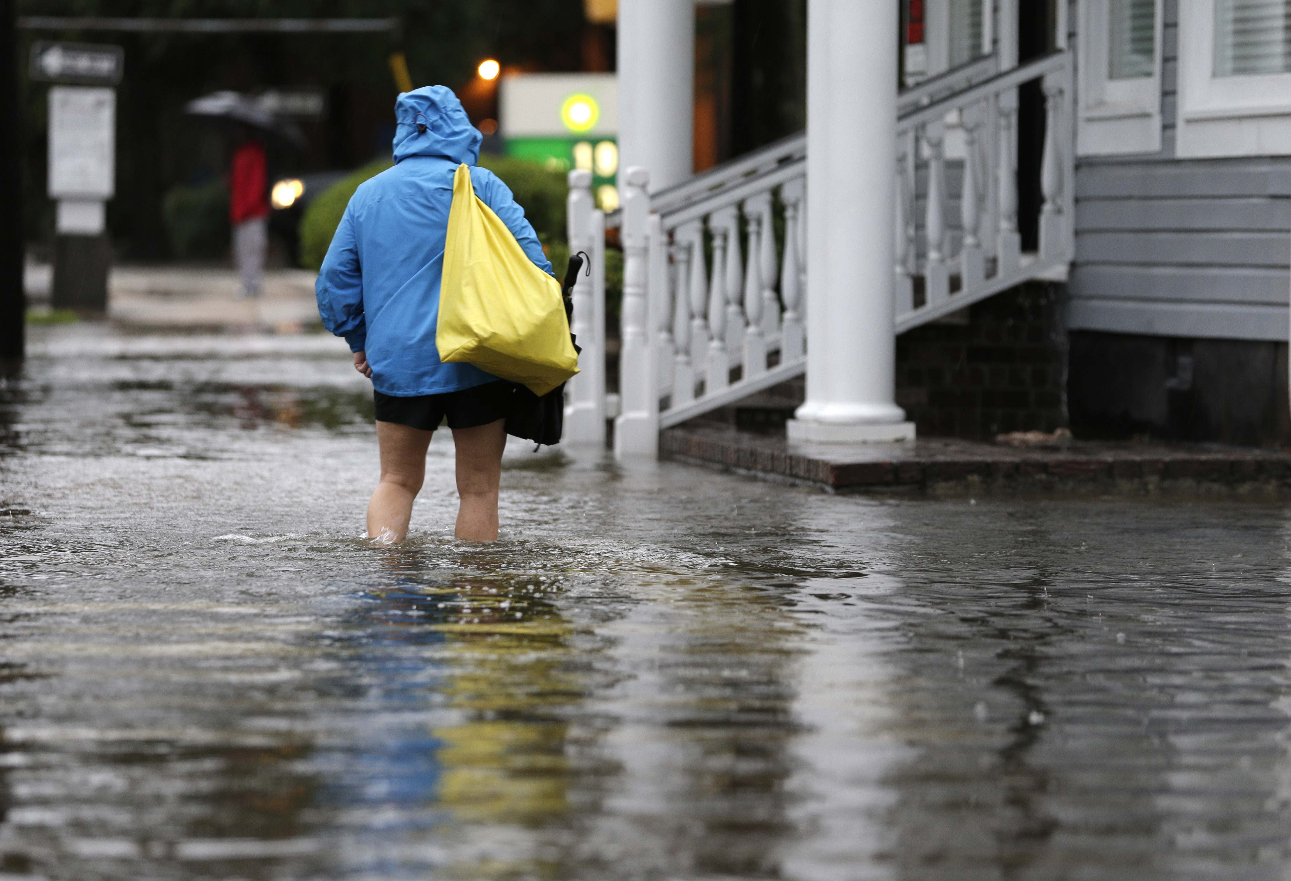 A woman walks down a flooded sidewalk toward an open convenience store in Charleston, S.C., Sunday, Oct. 4, 2015.