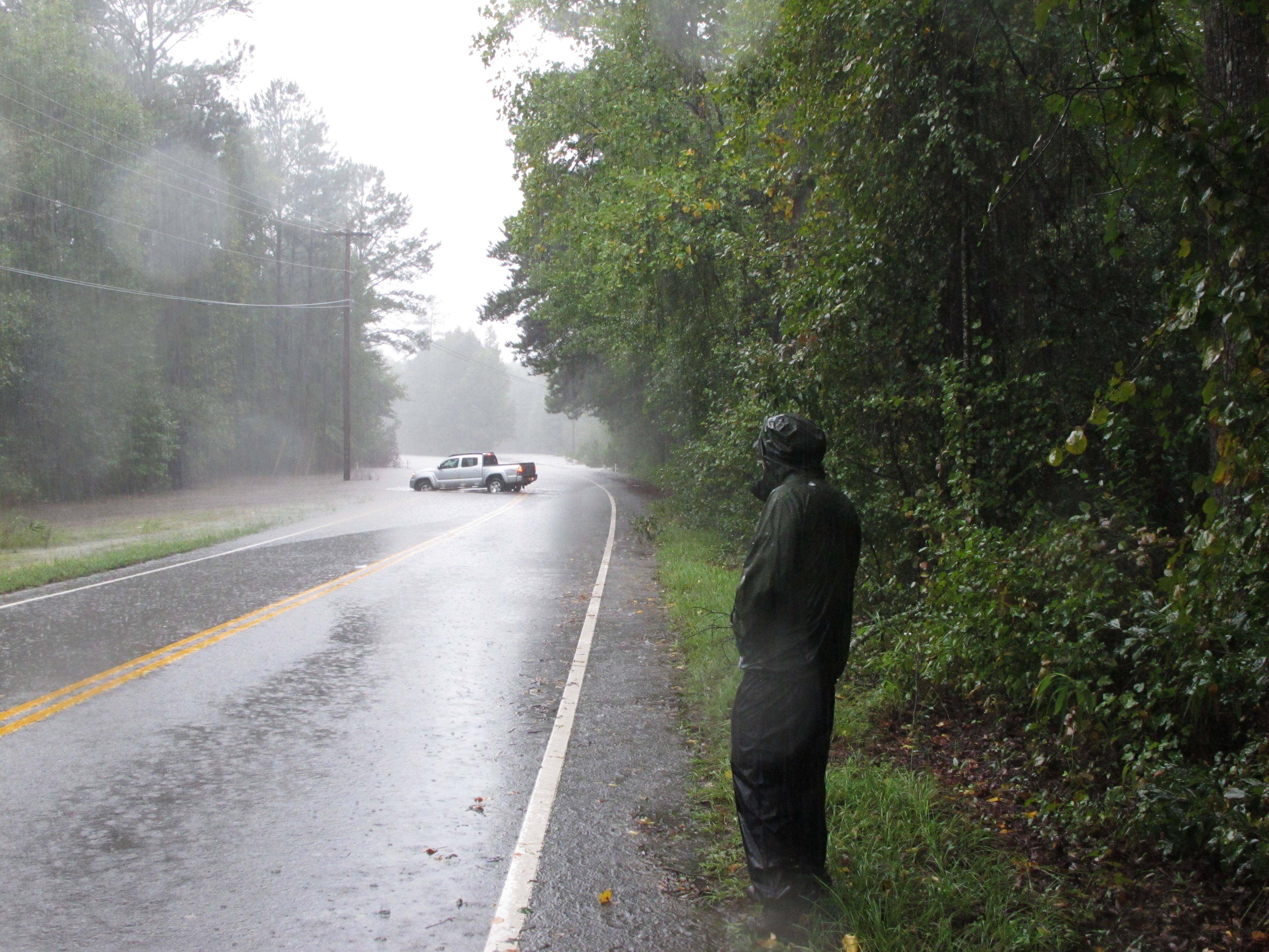 Fred Grooms watches as a car turns around in flood waters on Hardscrabble Road on Sunday, Oct. 4, 2015, in Columbia, S.C.