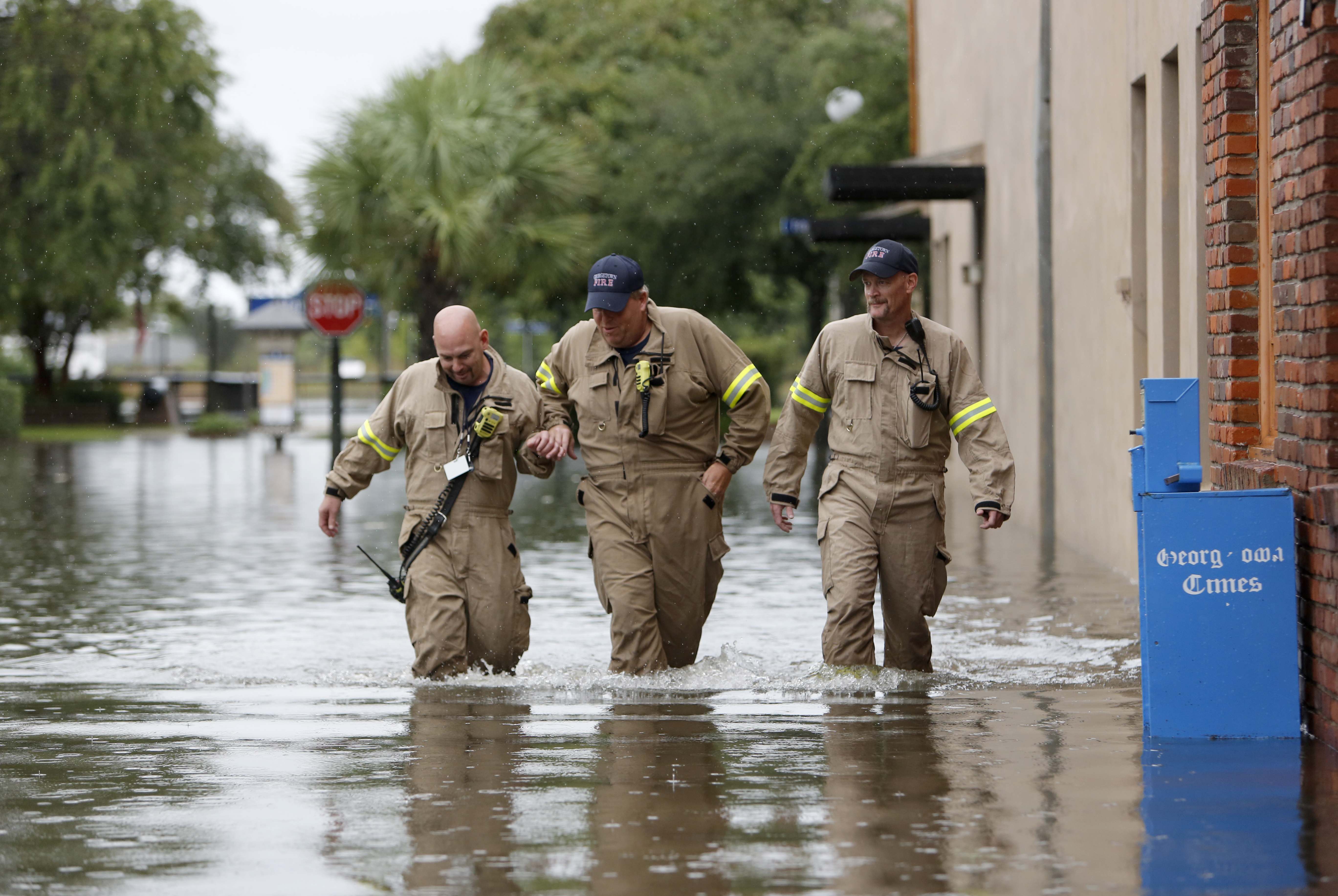 Firemen, from left to right, Norman Beauregard, Kevin Ettenger and Chris Rodgers with the Georgetown Fire Department, inspect the flood waters at high tide in the historic downtown in Georgetown, S.C., Sunday, Oct. 4