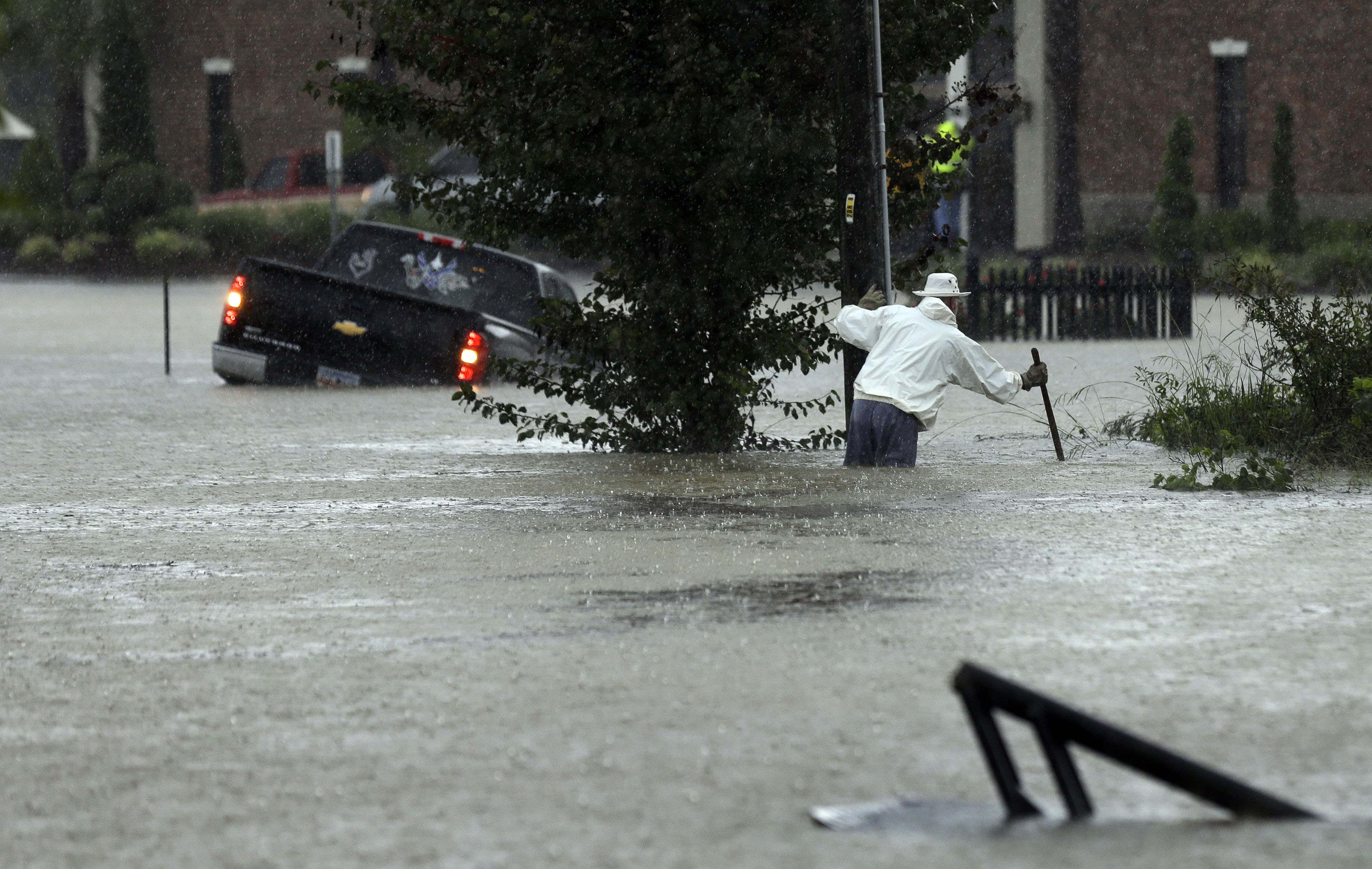 A vehicle and a man try to navigate floodwaters in Florence, S.C., Sunday, Oct. 4, 2015, as heavy rain continues to cause widespread flooding