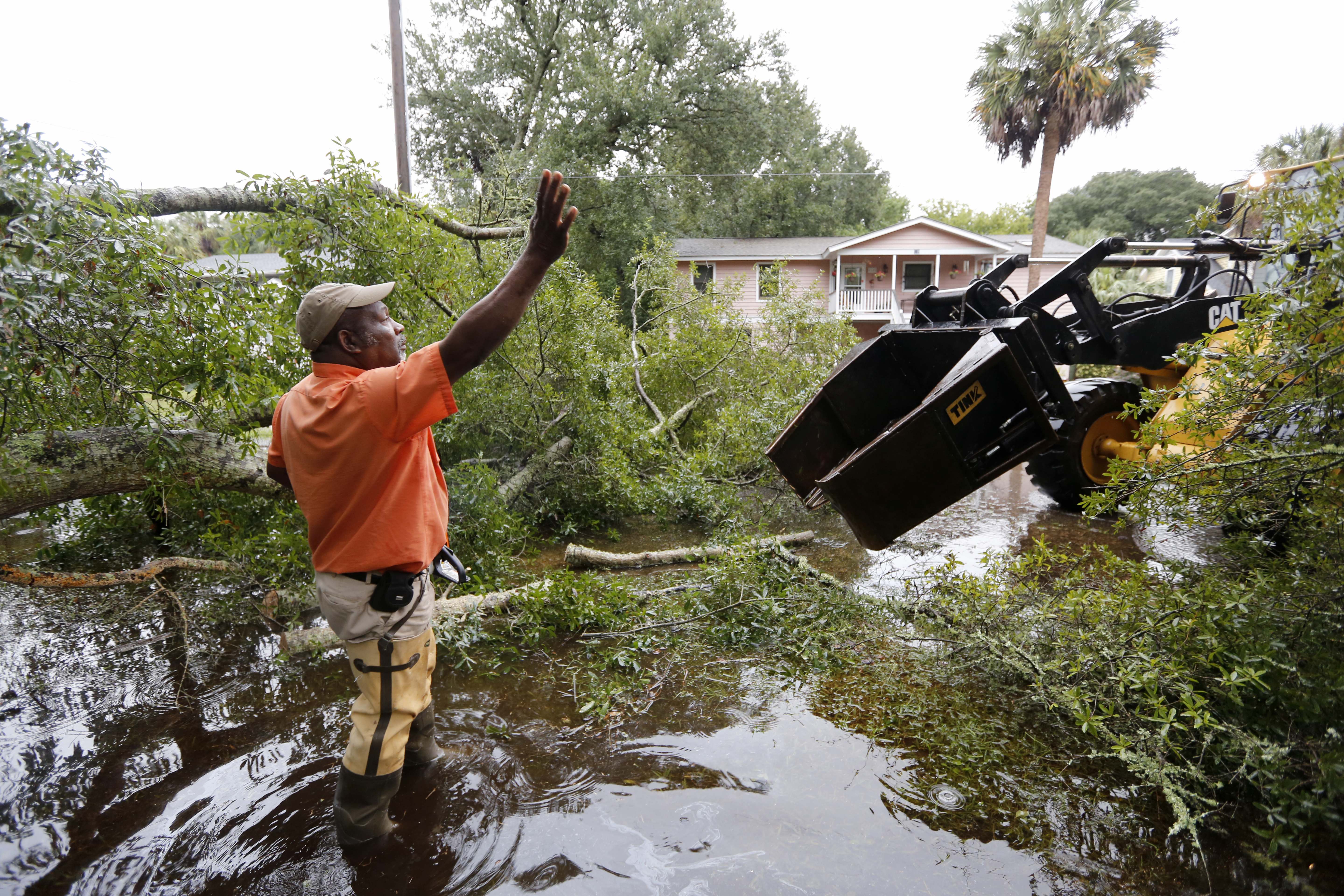 George Myers with the city of Isle of Palms directs equipment in on 23rd Ave. to clear the road after heavy rains fell on the Isle of Palms, S.C., Sunday, Oct. 4, 2015