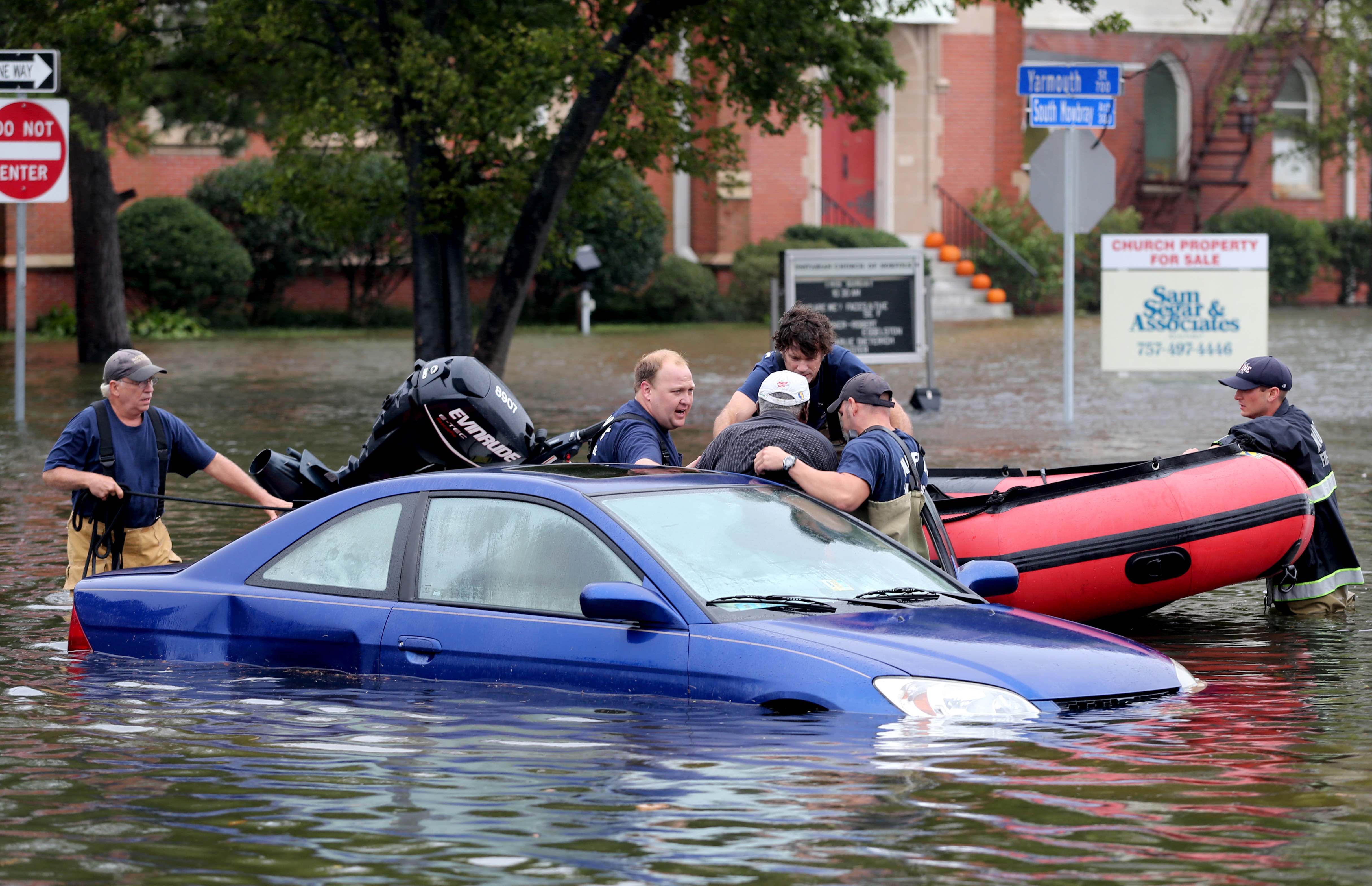 Members of Norfolk Fire-Rescue pull a man from his car stranded because of flooding in Norfolk, Va., on Sunday, Oct. 4, 2015.