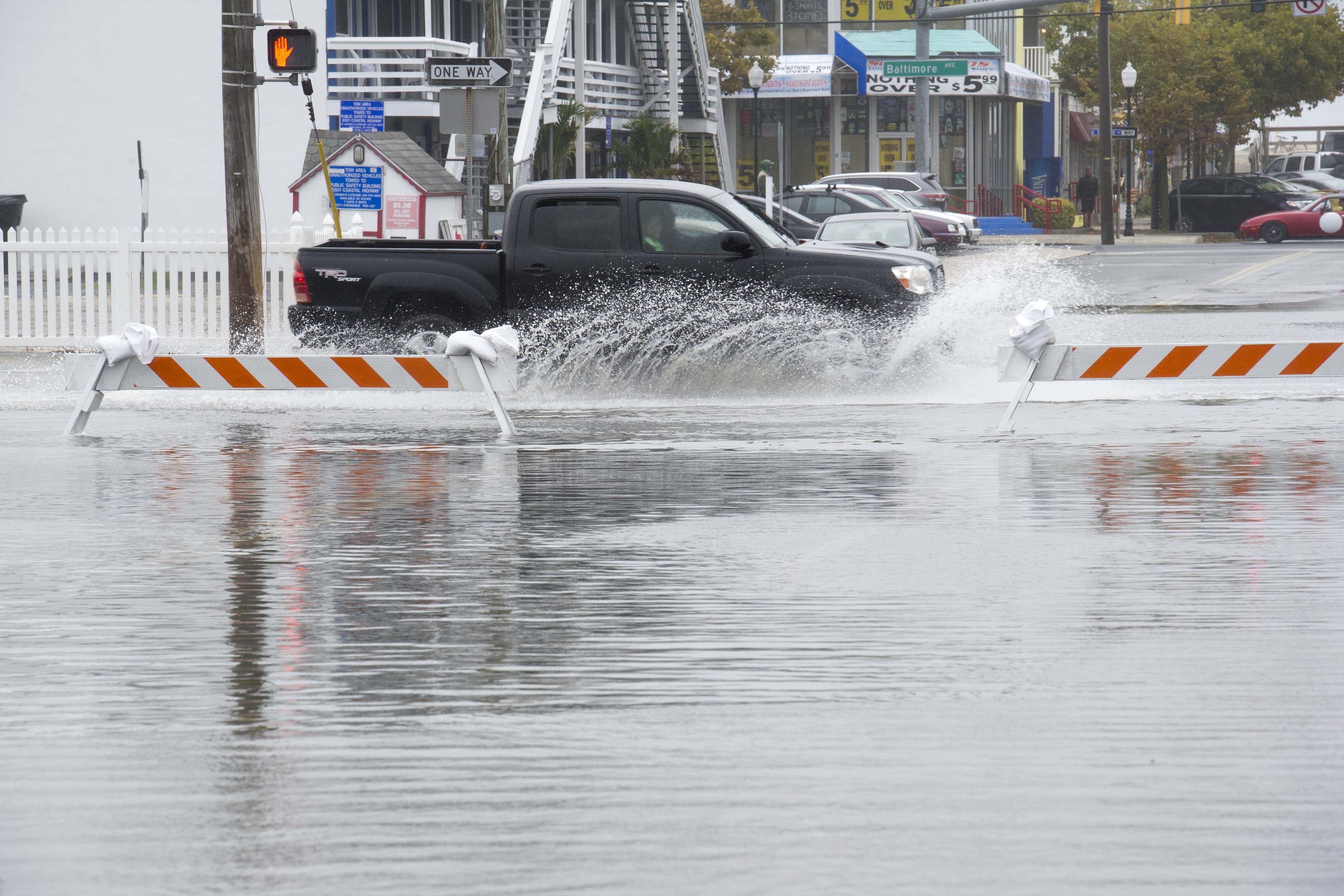 Traffic drives on flooded roads, at high-tide, in downtown Ocean City, Md., Saturday, Oct. 3, 2015. 