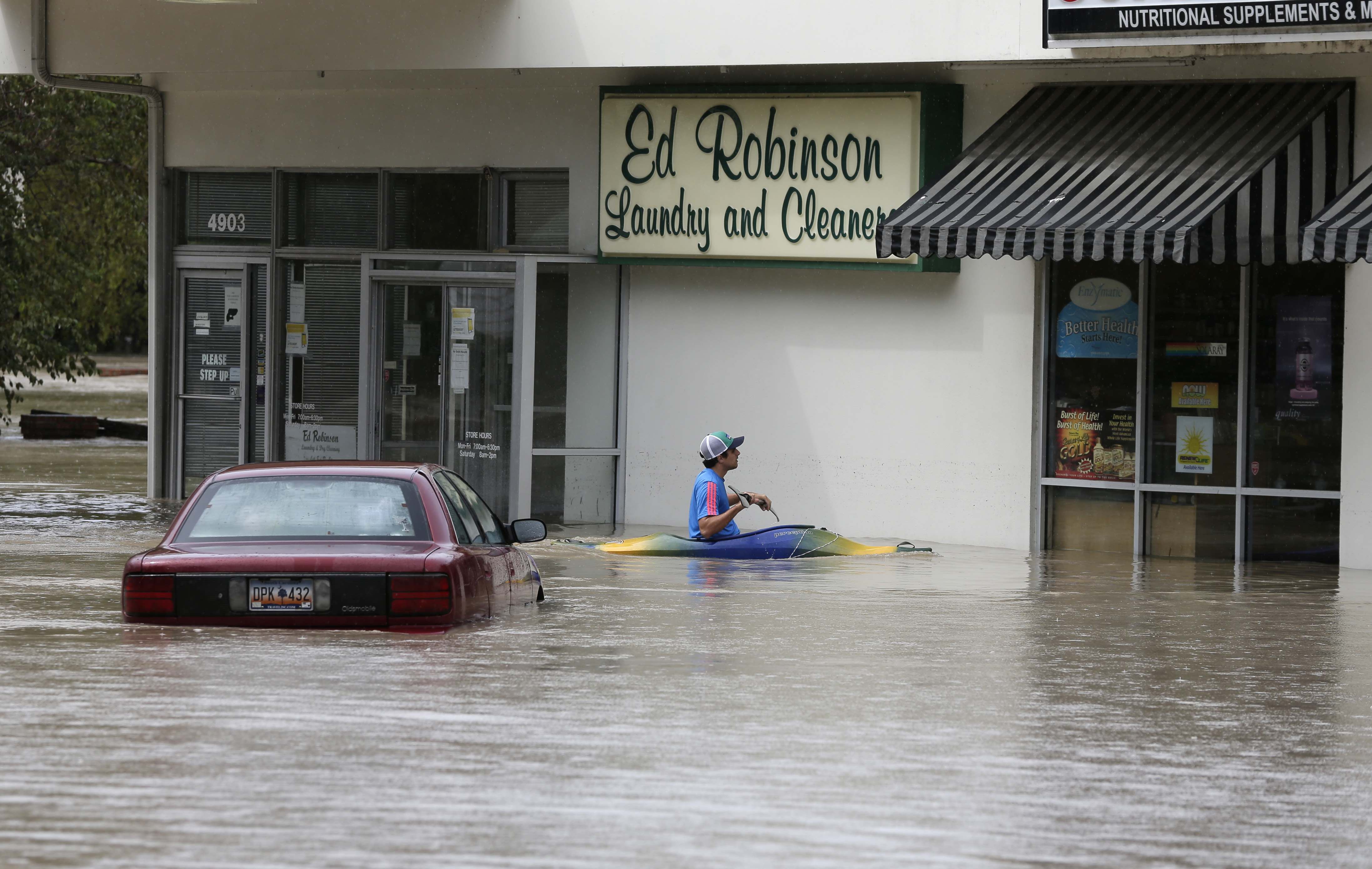 Jordan Bennett, of Rock Hill, S.C., paddles up to a flooded store in Columbia, S.C., Sunday, Oct. 4, 2015.