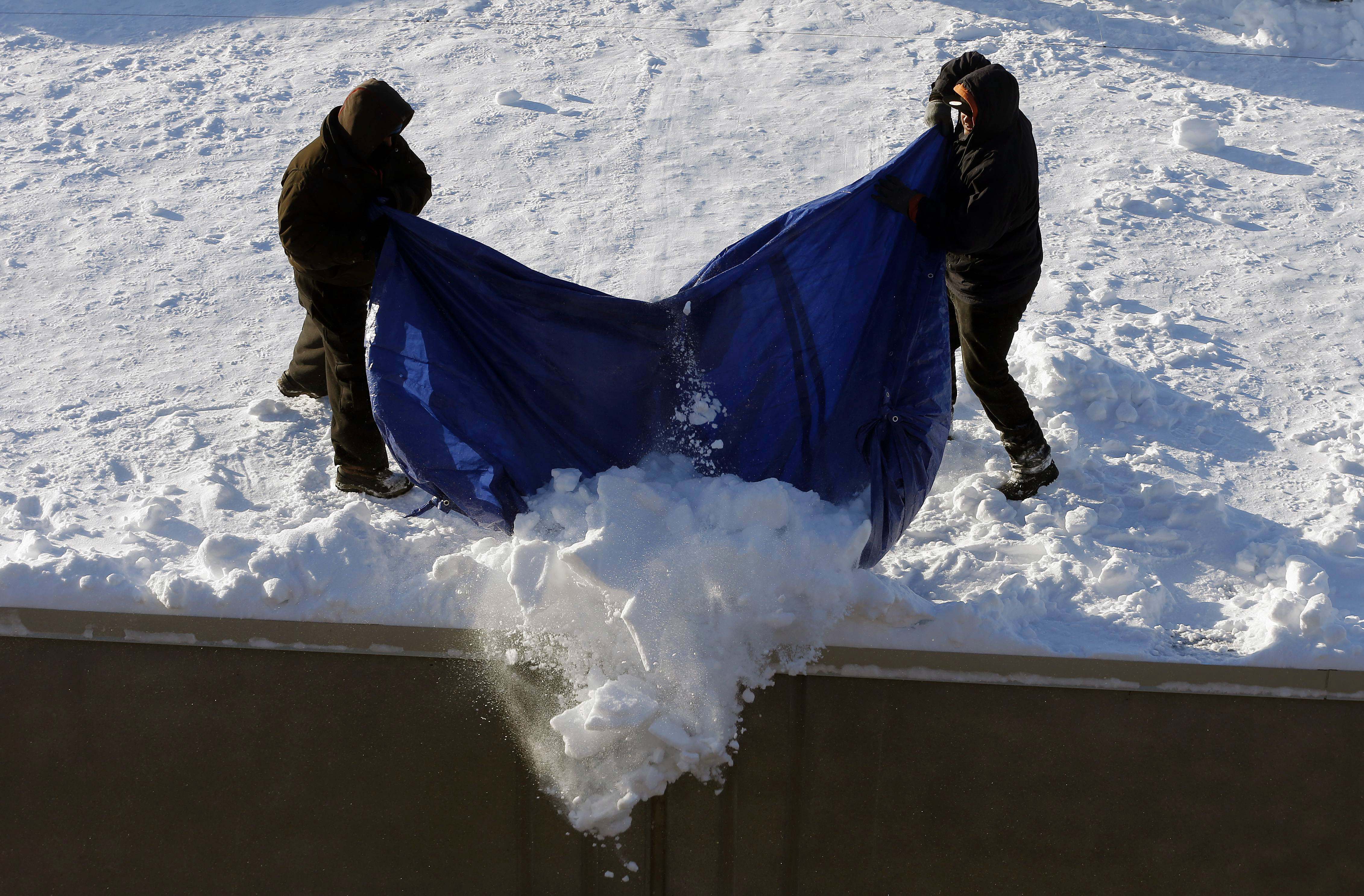 Workers clear snow from a roof in Boston, Monday, Feb. 16, 2015.