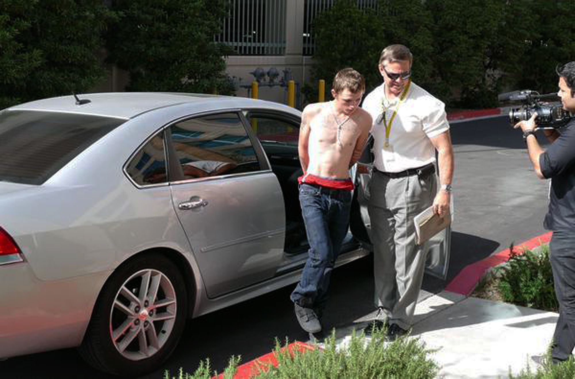 police official leads Erich Nowsch, 19, from a car to police headquarters for questioning in Las Vegas,