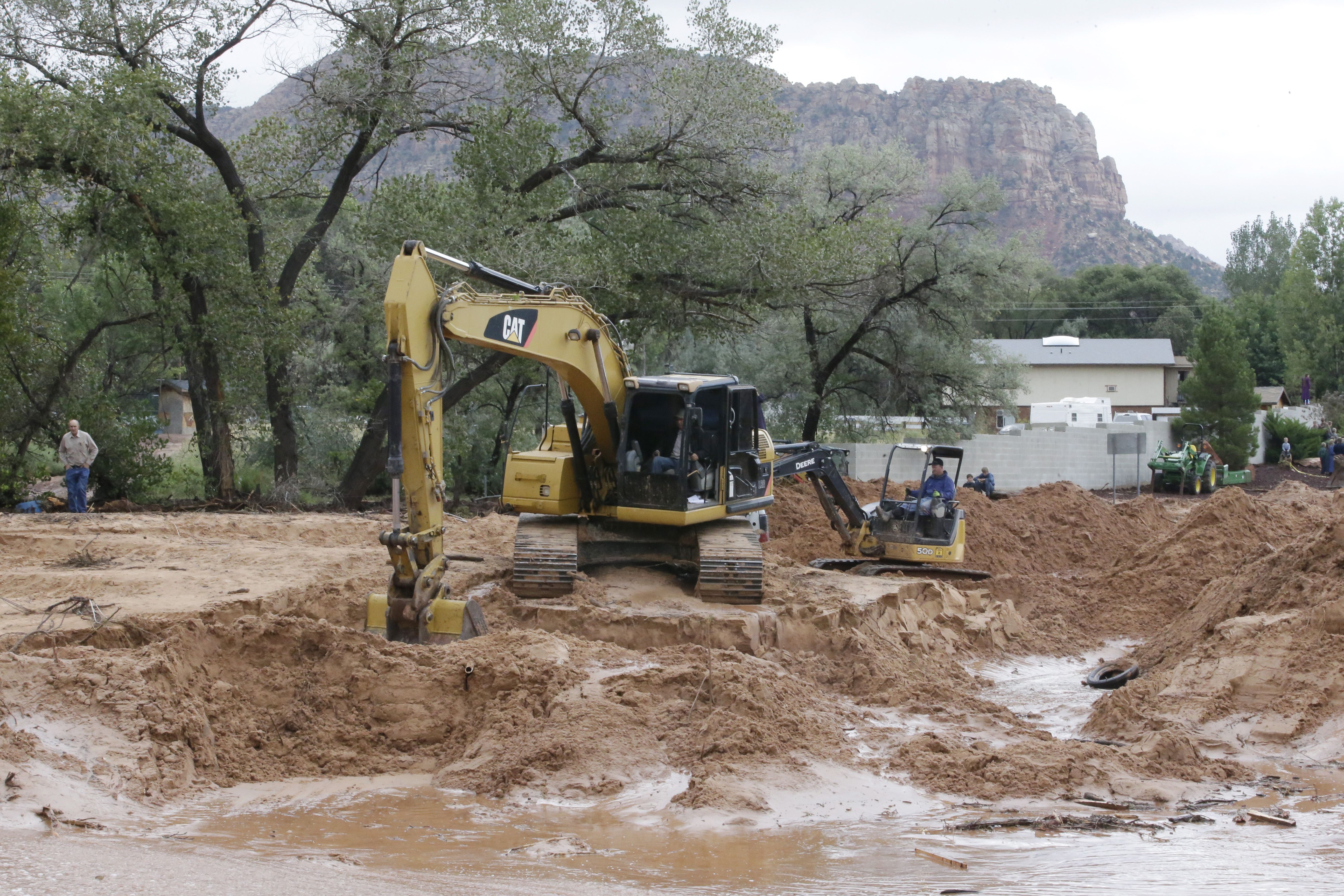 Crews clear mud and debris from a road following a flash flood Tuesday, Sept. 15, 2015, in Colorado City, Ariz. 
