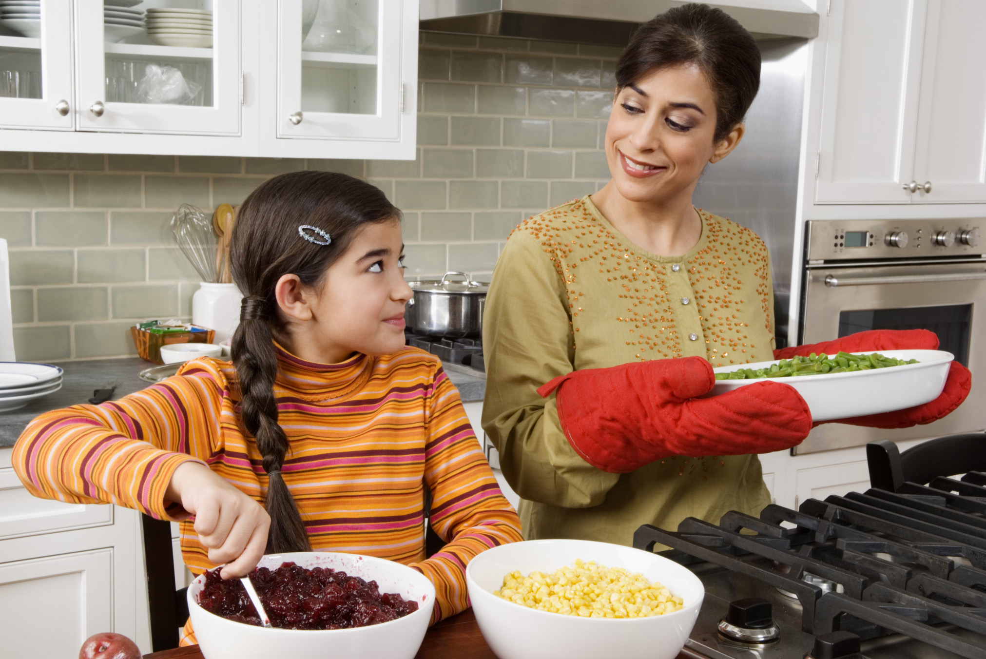 Woman-cooking-with-daughter-holding-pan-with-oven-mitts-crop-ThinkstockPhotos-76766403-Creatas Images