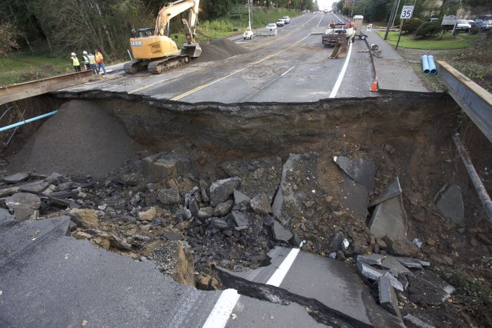 Maintenance personnel look at a large sinkhole on Kane Drive in Gresham, Ore.