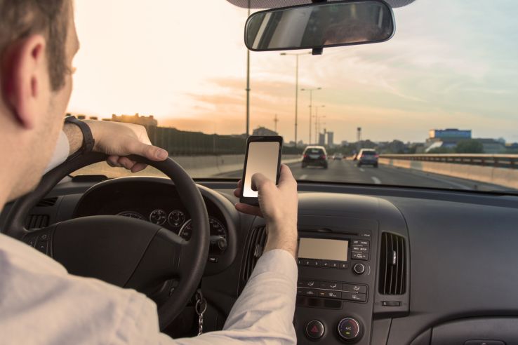 man driving down highway using smartphone