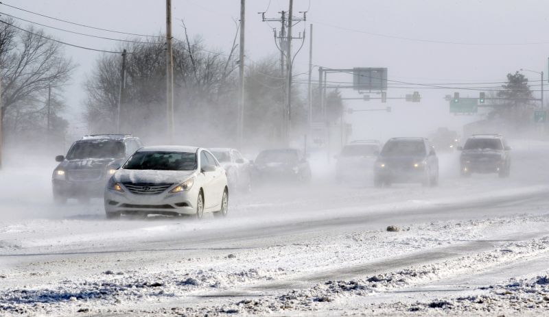 Motorists drive their cars through blowing snow Sunday, Feb. 15, 2015, in Yardley, Pa.