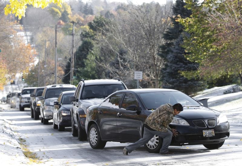 A good Samaritan helps push a car stuck on an icy road in Omaha, Neb., Tuesday, Nov. 11, 2014. 