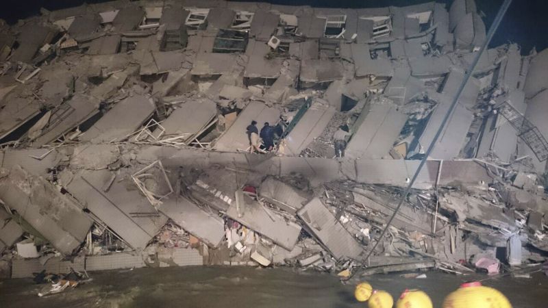 Rescuers are seen entering an office building that collapsed on its side from an early morning earthquake in Tainan, southern Taiwan