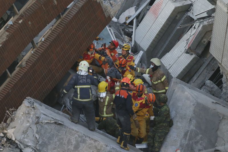 Rescue workers carry a 28-year-old Vietnamese woman, identified as Chen Mei-jih, rescued from the rubble of a collapsed building complex