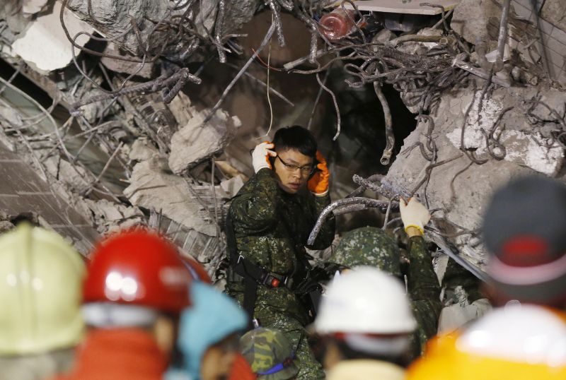 An army soldier tries to listen for signs of life in a collapsed building