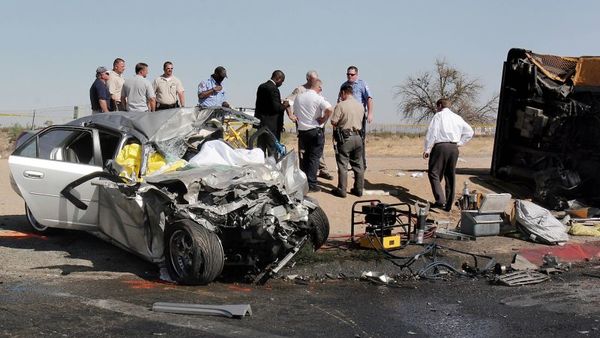 Investigators stand at the site of an accident, June 14, 2007, in Adelanto, Calif. A speeding car ran a stop sign, upending a school bus carrying young children and killing the car's passenger and critically injuring the teen driver, authorities said. (Photo: Dan Elliott/AP Photo)