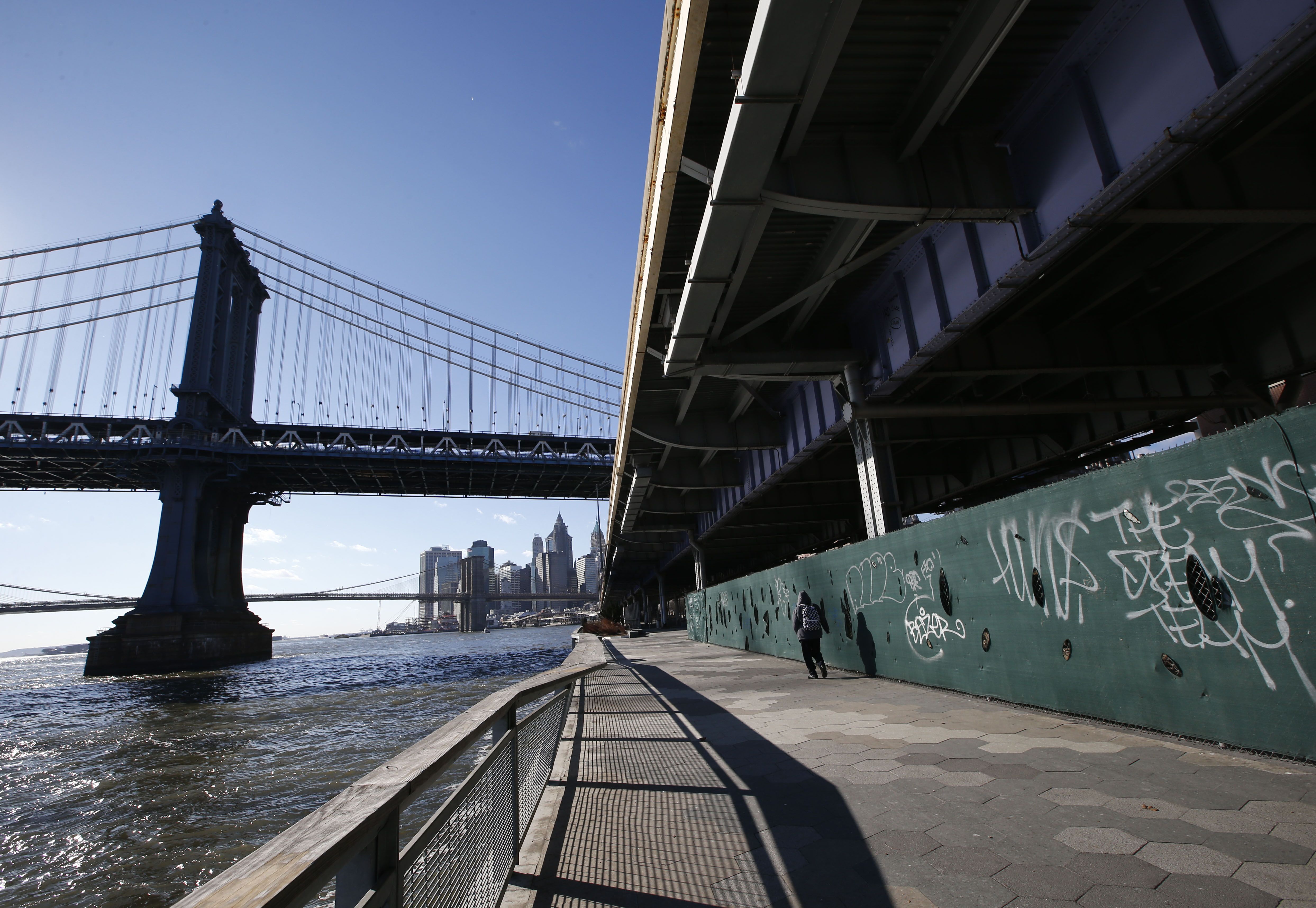 A pedestrian walks along the East Side Esplanade in an area beneath the FDR drive just north of the Manhattan Bridge