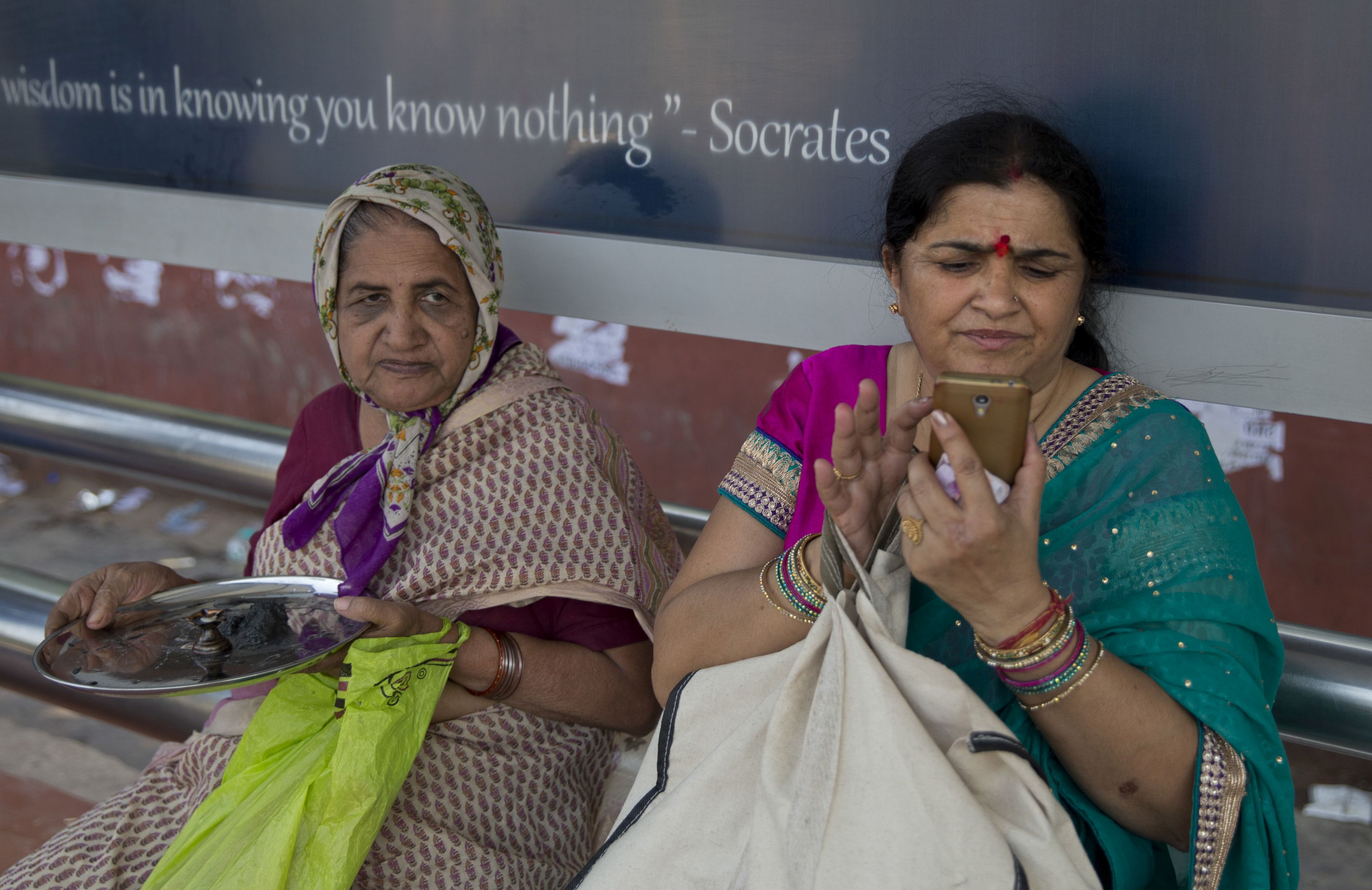 An Indian woman uses her mobile phone as she waits for a bus in New Delhi, India