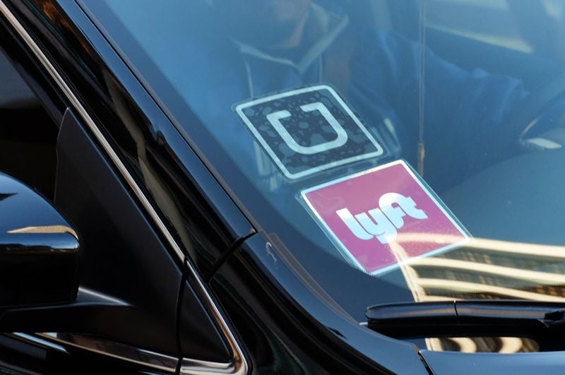 Uber and Lyft signs displayed on vehicle windshield