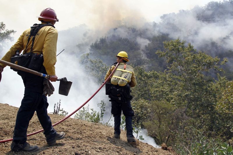 Firefighters watch as a wildfire burns west of Goleta, Calif.