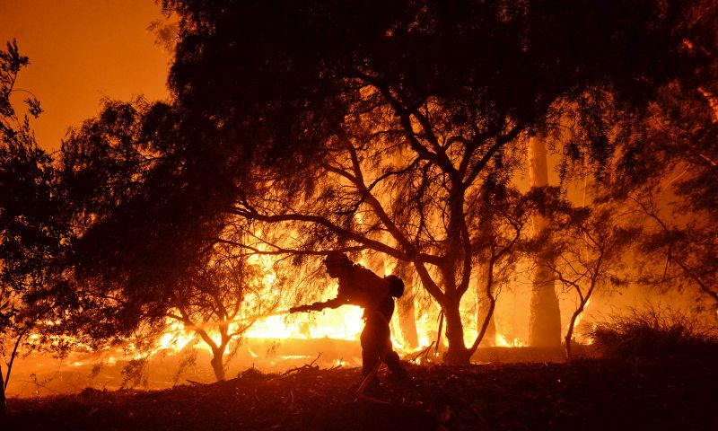 A firefighter knocks down flames as they approach a ranch near the Las Flores Canyon area west of Goleta, Calif.