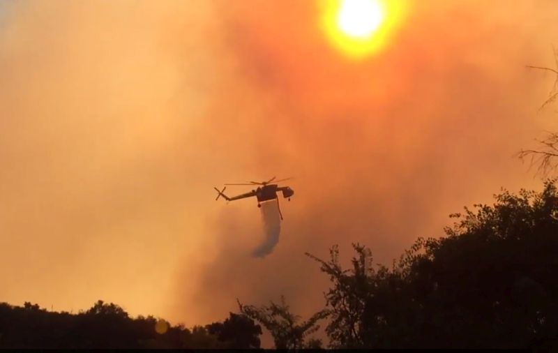 Helicopter makes a water drop over a wildfire in a remote coastal area west of Santa Barbara