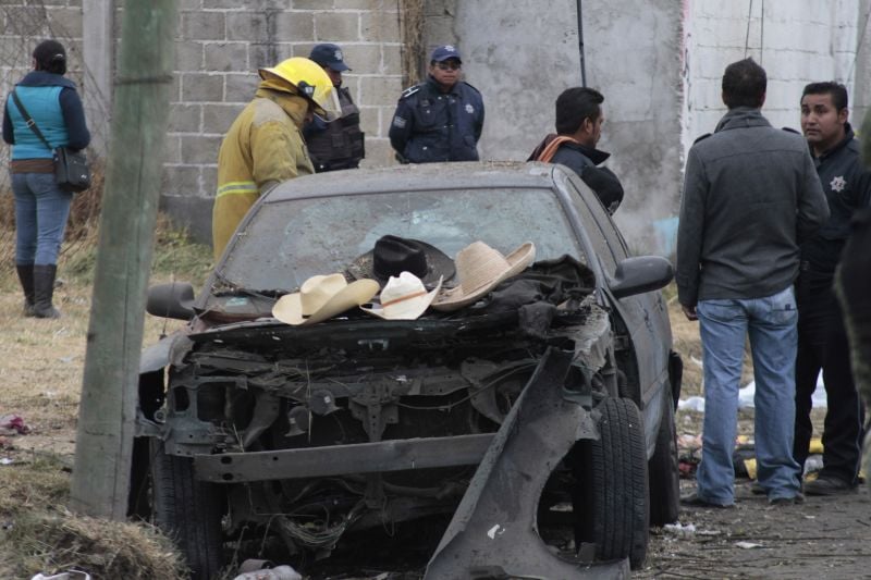 Hats belonging to victims sit on the hood of a damaged car