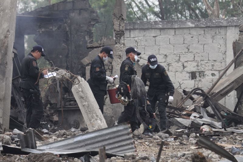Police investigators gather pieces of evidence at the site Friday Jan. 30, 2009, a day after a powerful explosion at a fireworks factory