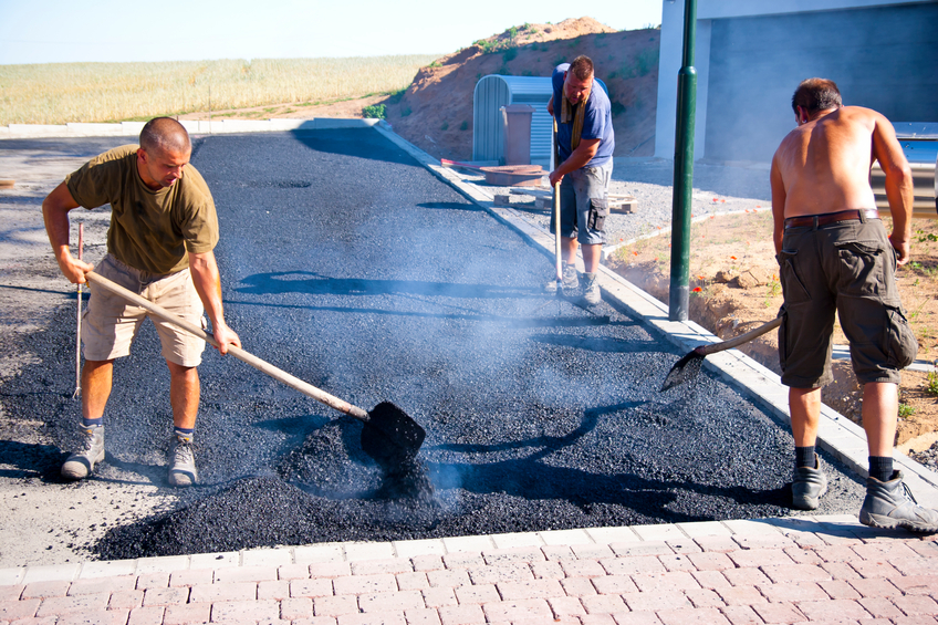 Workers spreading hot asphalt