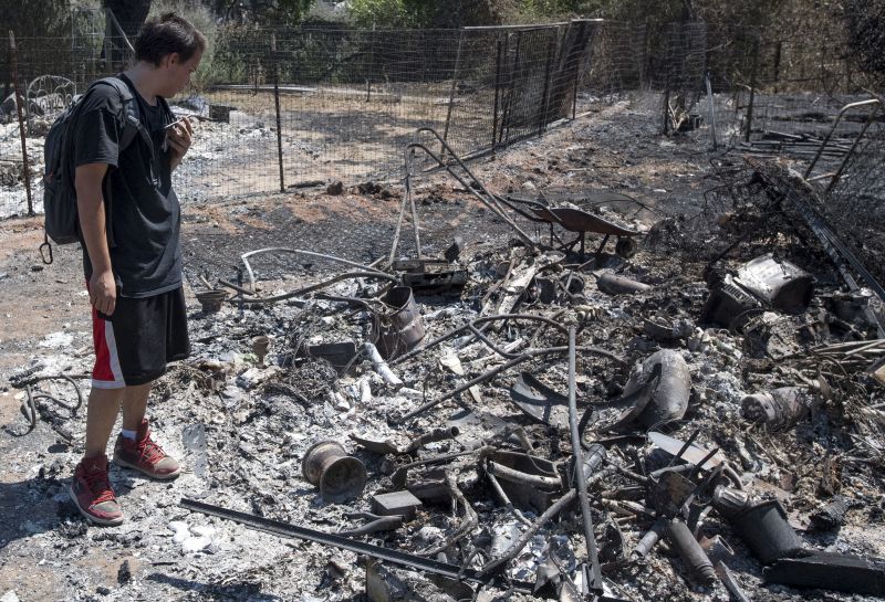 Daniel Brown uses a chat app with his mother while surveying damage to his home after a fire