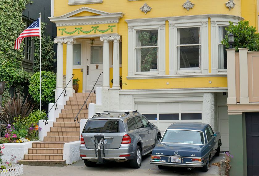 Vehicles in driveway in front of yellow house