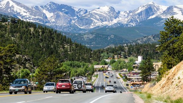 The road leading into Estes Park, Colorado, with traffic and snowcapped Rocky Mountains in the background. (Photo: iStock)