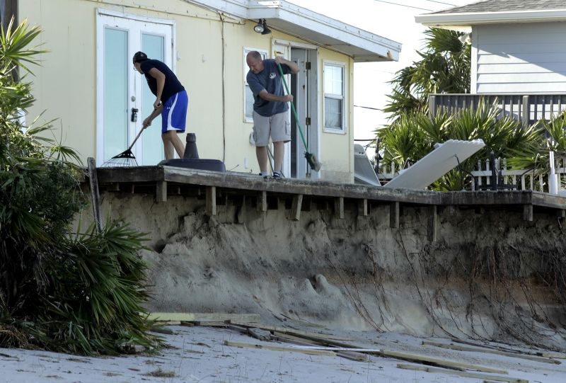 Rob Jakoby and his son Jake sweep debris off the eroded deck