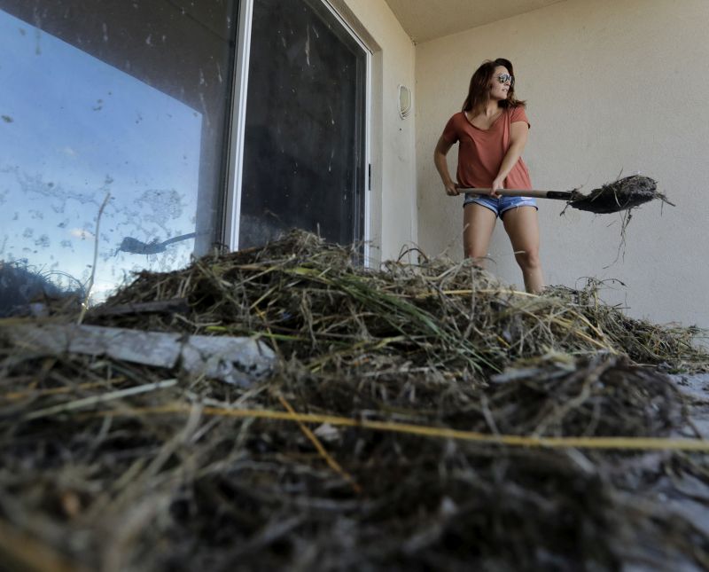 Danielle Henry clears debris from outside her condo at Jacksonville Beach, Fla.