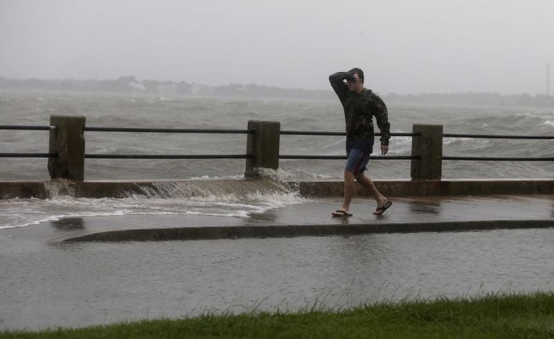 A man braces against the wind and waves as he walks down Bay Street in Charleston, S.C.