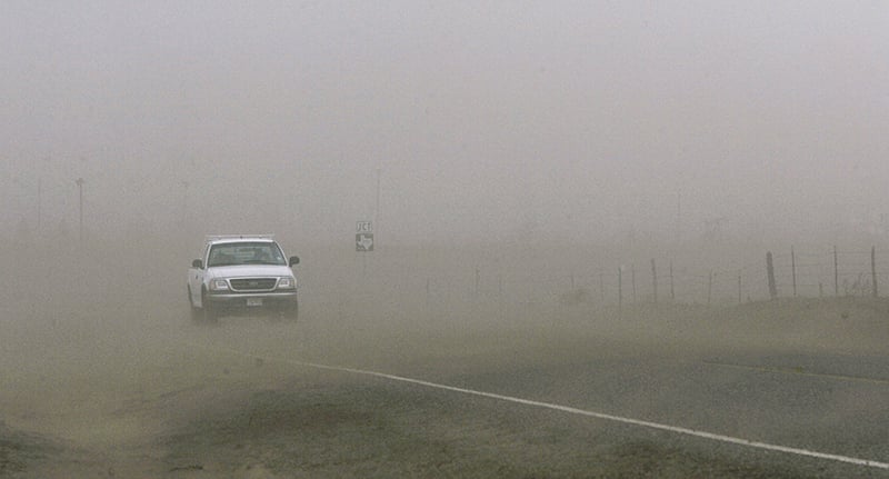 White pick up truck driving in Texas dust storm