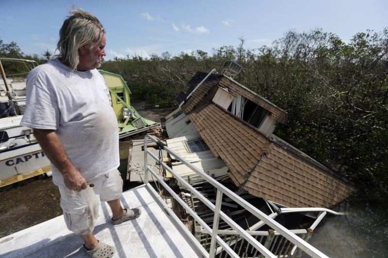 Donald Garner, 57, surveys the wreckage of another houseboat from the roof of his in Lower Matecumbe Key, Fla.