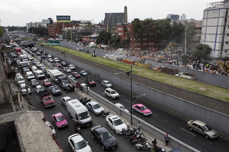 Rescue personnel work on a collapsed building, far right, as vehicle traffic crawls on the Viaducto highway, a day after a devastating 7.1 earthquake, in the Del Valle neighborhood of Mexico City, Wednesday, Sept. 20, 2107. Efforts continue at the scenes of dozens of collapsed buildings, where firefighters, police, soldiers and civilians continue their search to reach the living. (AP Photo/Moises Castillo)