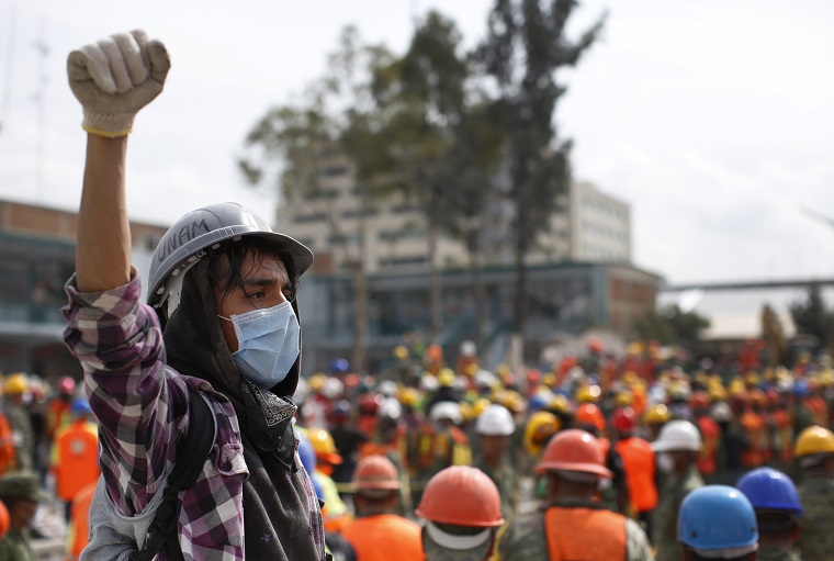 A young volunteer raises his fist as a sign to keep silent as dogs search through the rubble of a 7.1 quake-collapsed four-story clothing factory, in Mexico City, Friday, Sept. 22, 2017. Rescue operations stretched into a fourth day Friday, spurring hope among desperate relatives gathered at the sites of buildings collapsed by Tuesday's powerful earthquake. (AP Photo/Dario Lopez-Mills)