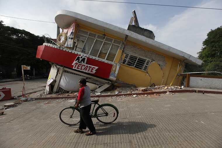 A man walks his bike past a building felled by a 7.1 earthquake, in Jojutla, Morelos state, Mexico, Wednesday, Sept. 20, 2017. Buildings collapsed in Morelos state, including the town hall and local church in Jojutla near the quake's epicenter. (AP Photo/Eduardo Verdugo)