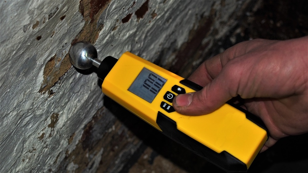 man measuring the moisture in a concrete wall