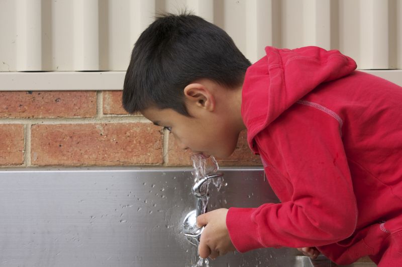 boy drinking from a water fountain